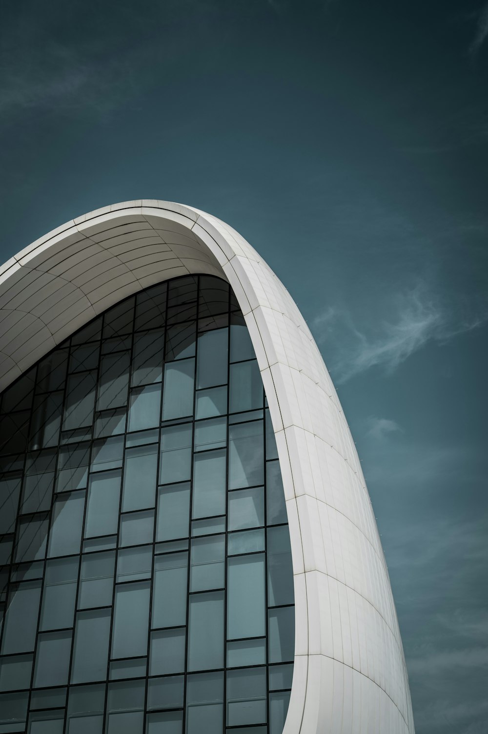 a tall building with a curved roof and a sky background