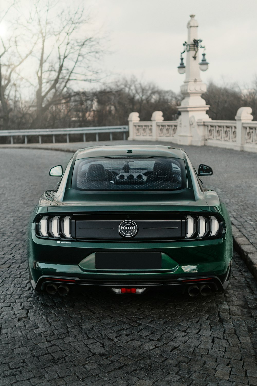 a green car parked on a cobblestone road