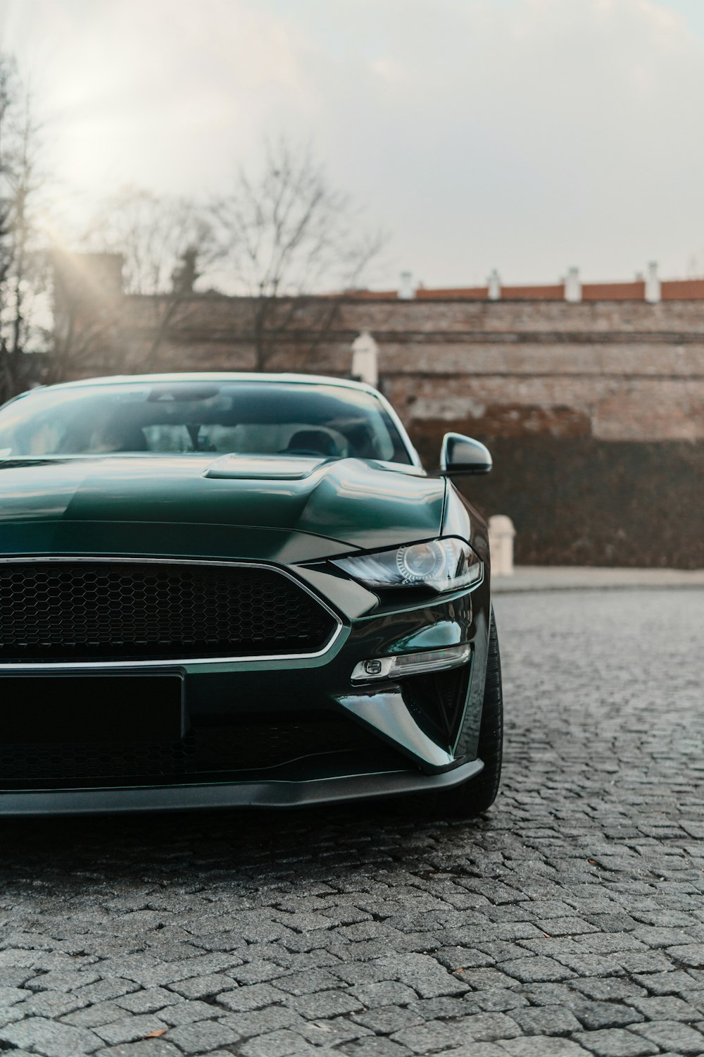 a green sports car parked on a cobblestone road