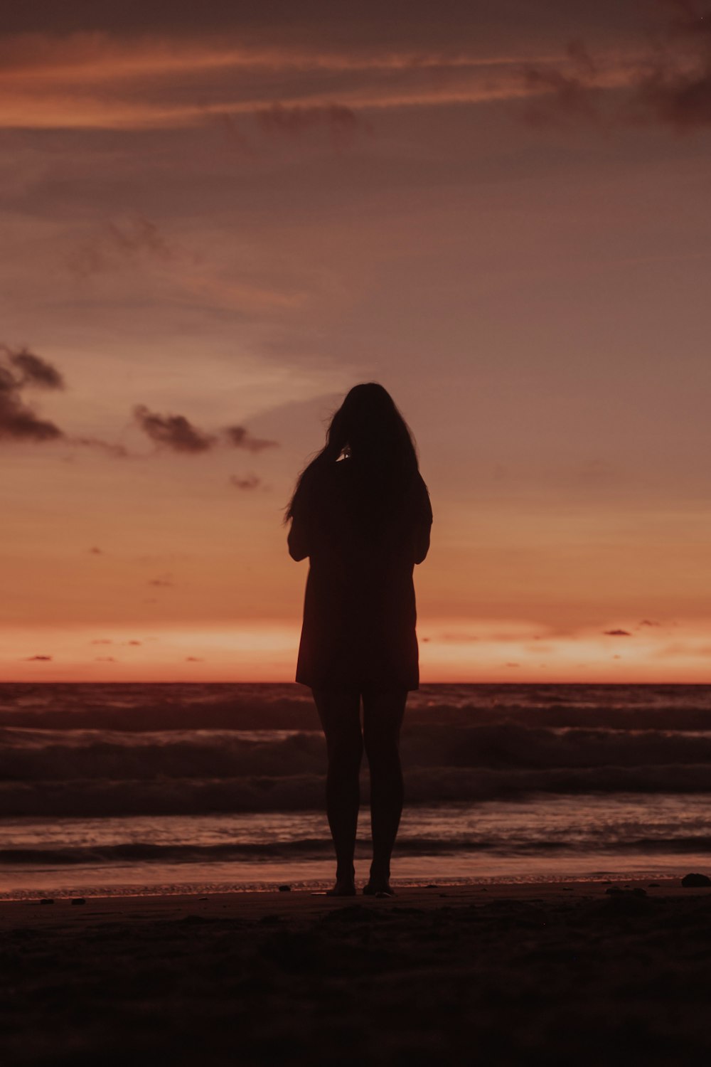 a person standing on a beach with a sunset in the background