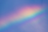 Colorful abstract album cover featuring a shimmering rainbow beneath soft clouds.