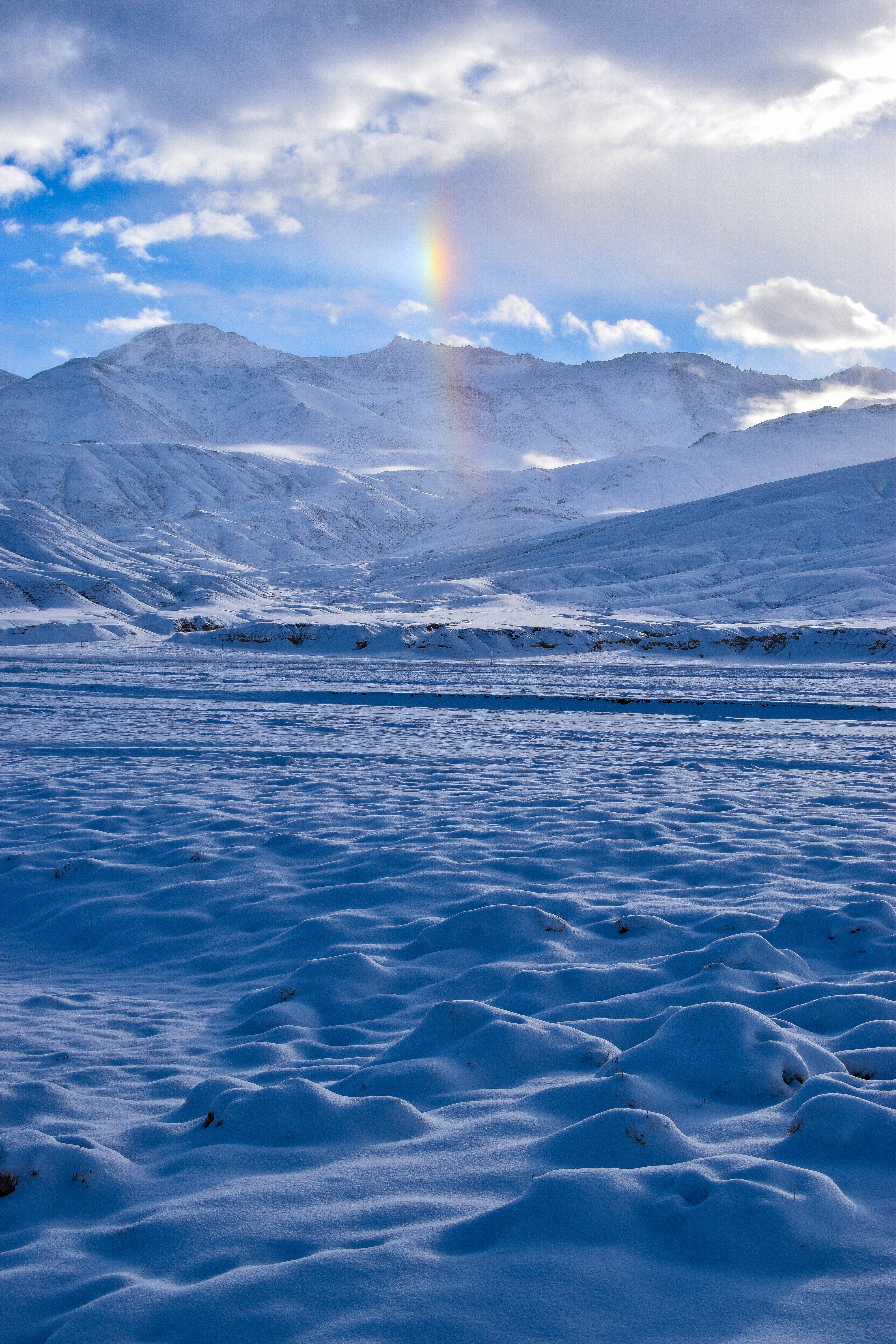 a rainbow shines in the sky over a snowy landscape