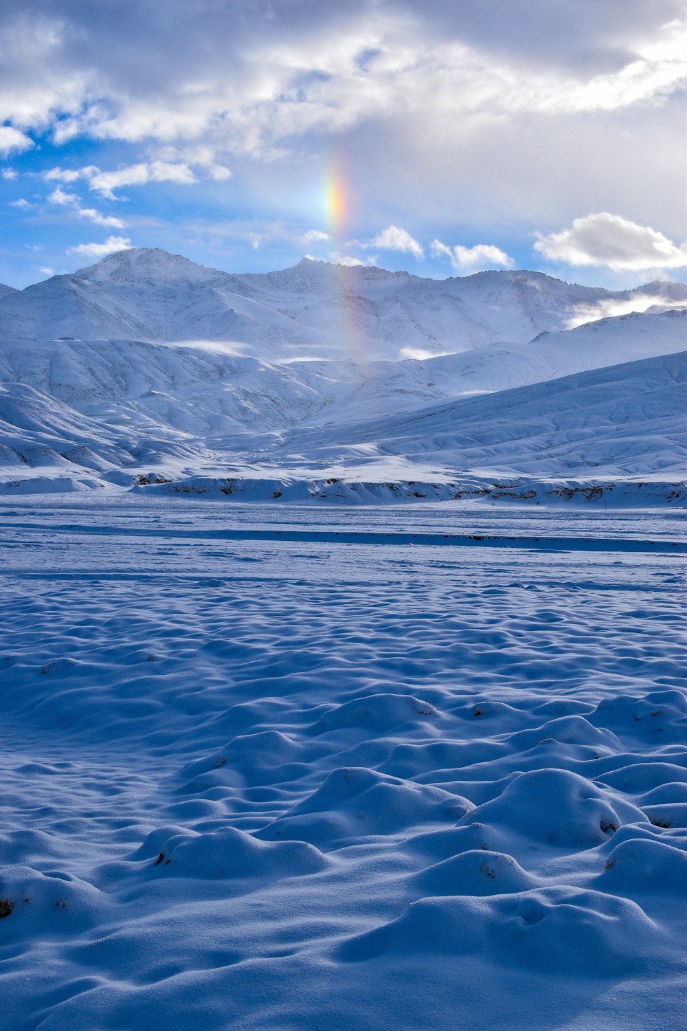 a rainbow shines in the sky over a snowy landscape