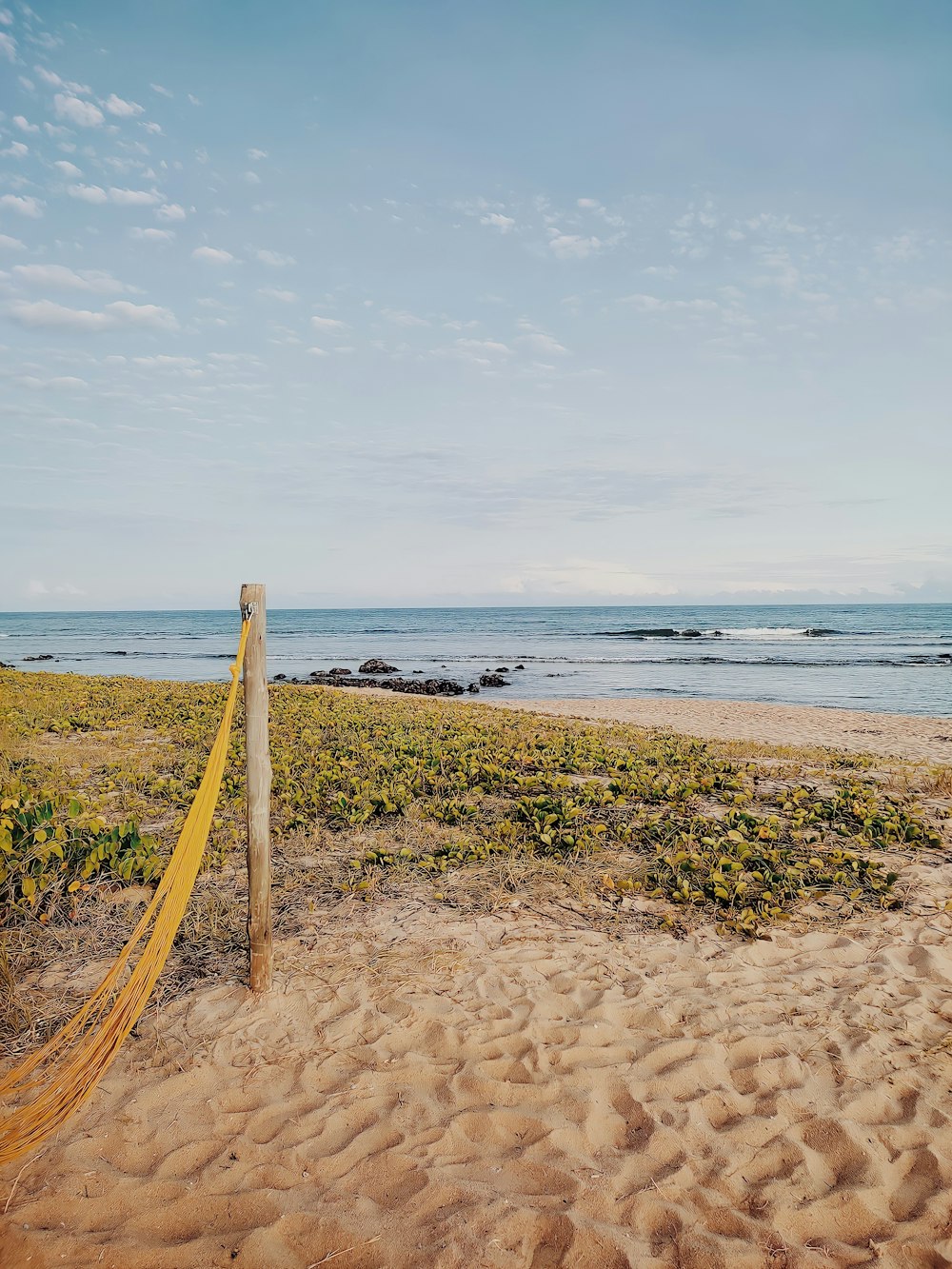 a beach with a fence and a body of water in the background