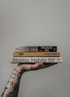 a person holding a stack of books in their hand