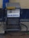 An old-fashioned diesel fuel pump located on a concrete slab. The pump has a metallic exterior with a hose attached, and the words 'DIESEL' and 'DED' prominently displayed. It's a rainy day, evident from the visible rain streaks and wet surfaces around the pump.