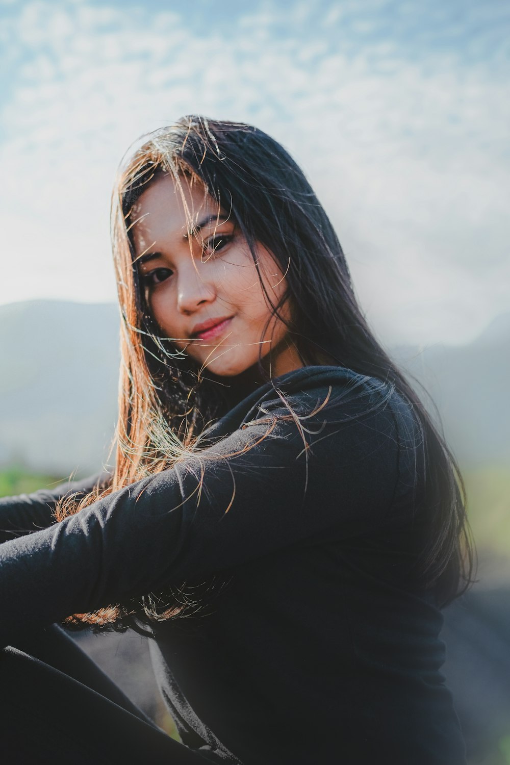 a woman with long hair sitting on the ground