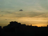 A cinematic frame showing a dramatic sunset behind a silhouetted cityscape.