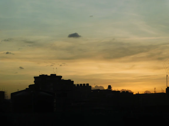 A cinematic frame showing a dramatic sunset behind a silhouetted cityscape.