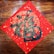 A decorative piece of art features intricate gold and black designs on a red square, possibly depicting stylized clouds and abstract Chinese characters. The artwork is set against a wooden background.