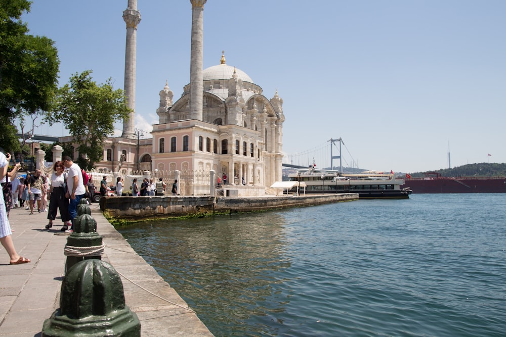 a group of people walking on a sidewalk next to a body of water