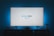 A television screen displays the Prime Video logo, situated on an entertainment unit in a dimly lit room. The room is illuminated with a subtle blue backlight, creating a calming atmosphere. Two small decorative items, resembling mushrooms, are placed on either side of the unit.