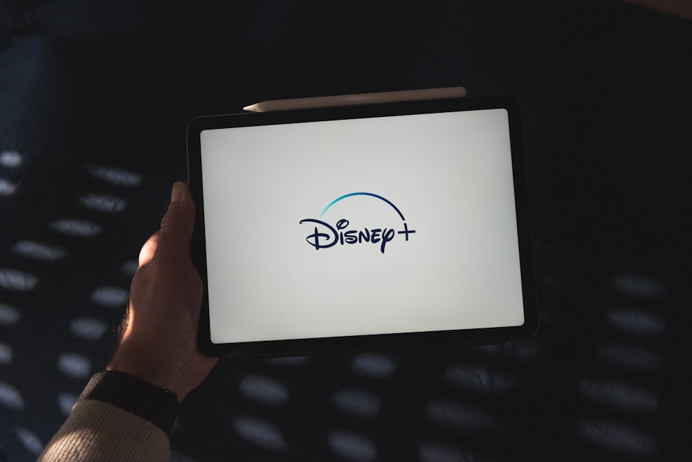 a person holding a tablet with a disney logo on it