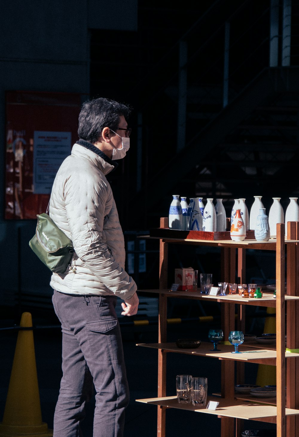 a man wearing a face mask standing in front of a shelf of bottles