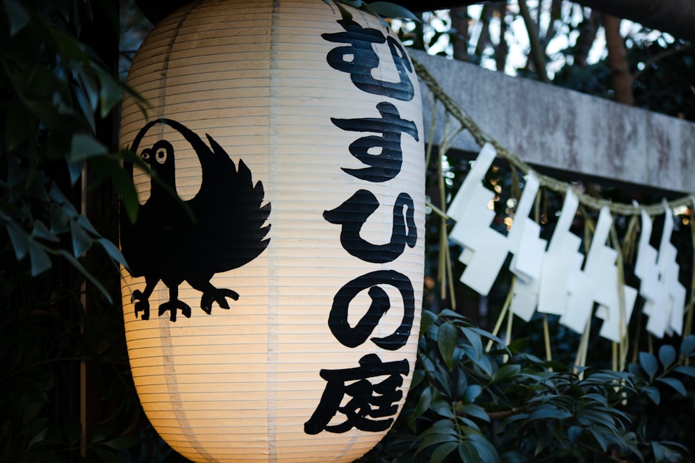 a lantern with a bird on it hanging from a tree