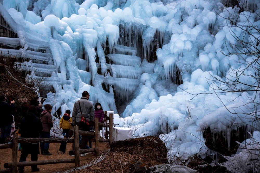 a group of people standing in front of a frozen waterfall
