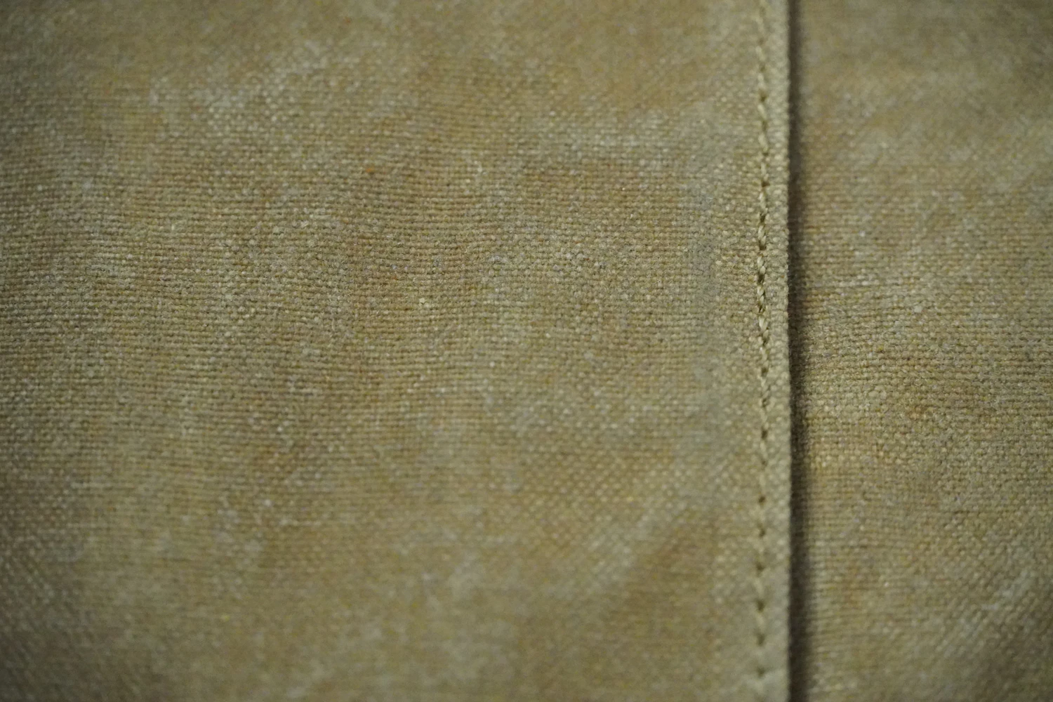 A seam running across olive cotton canvas