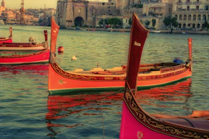 Colorful traditional Maltese fishing boats bobbing in the clear blue harbor.