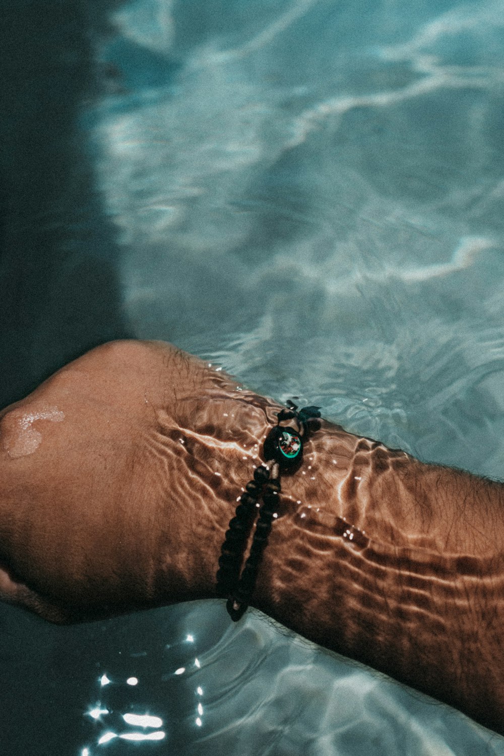 a person's arm in the water with a bracelet on it