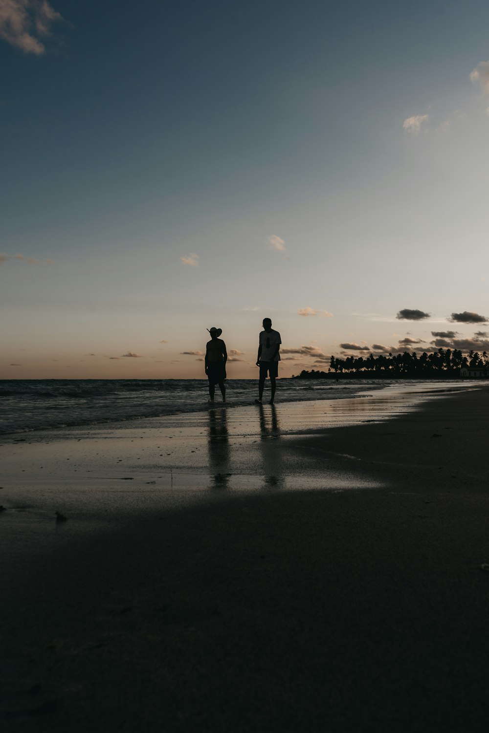 a couple of people standing on top of a beach