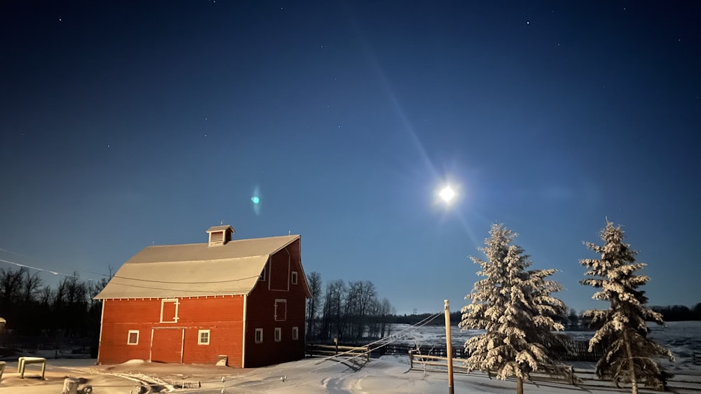 a red barn in the middle of a snowy field