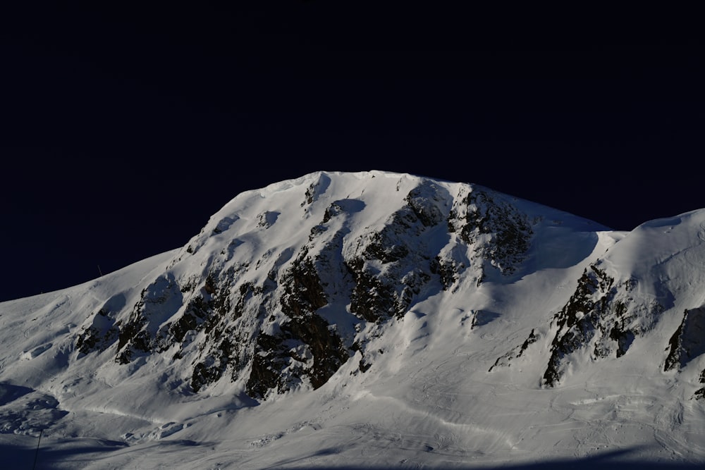 a large mountain covered in snow under a dark sky