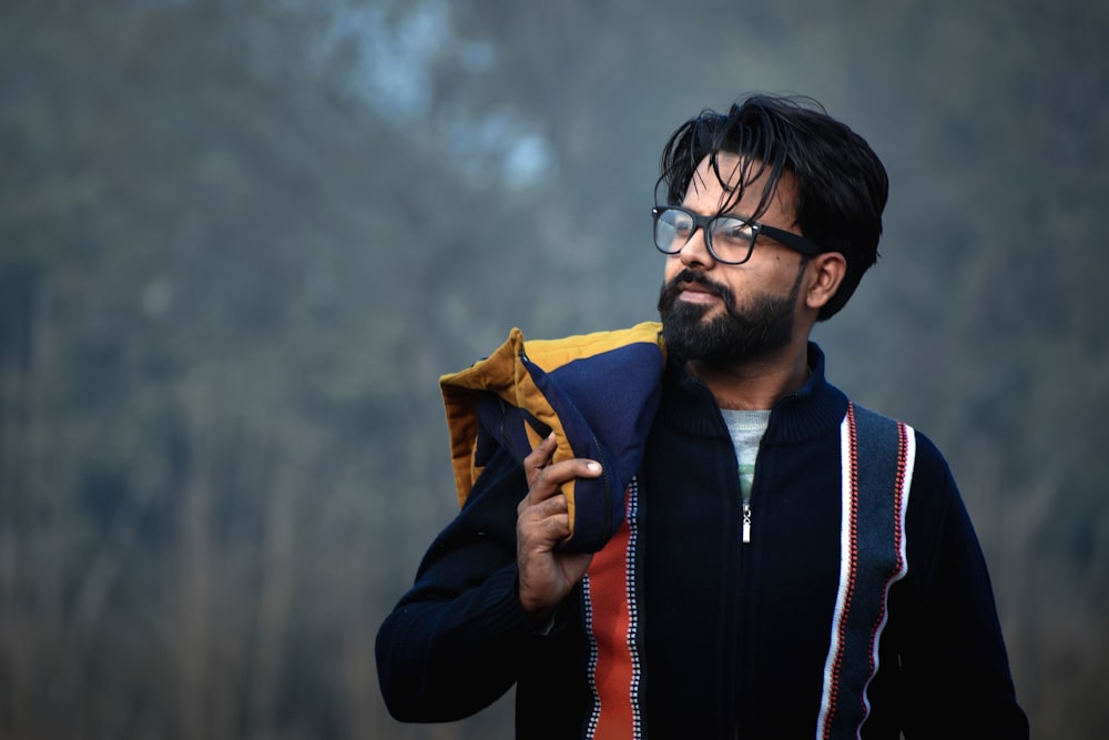 a man with glasses holding a jacket in his hand