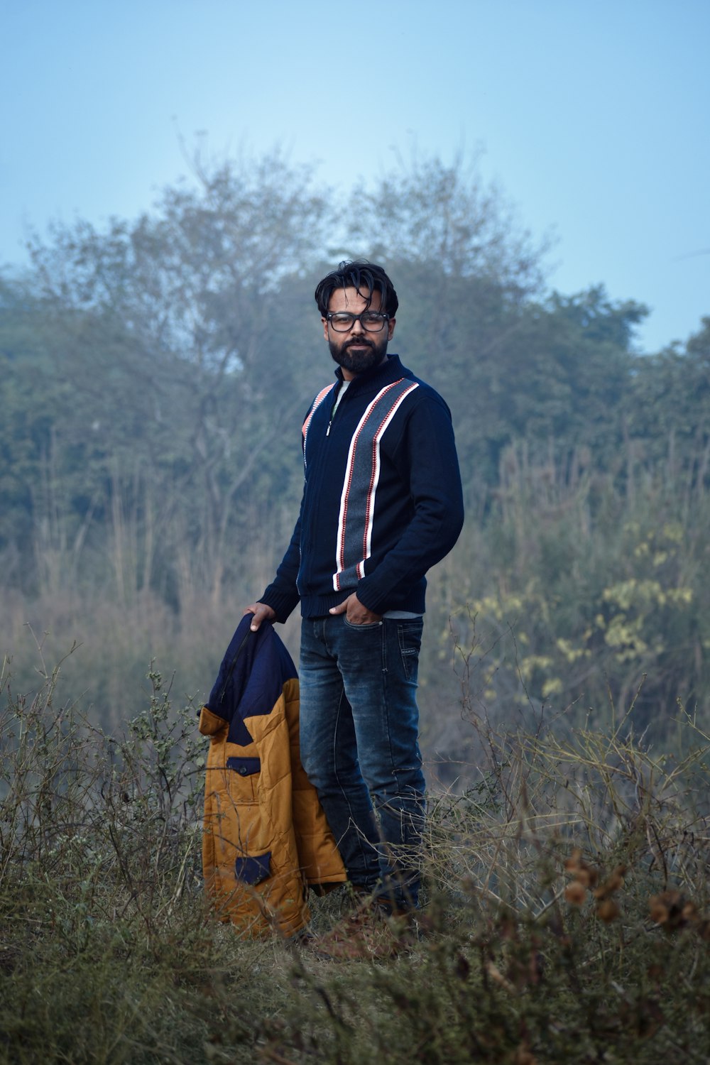 a man standing in a field with a backpack