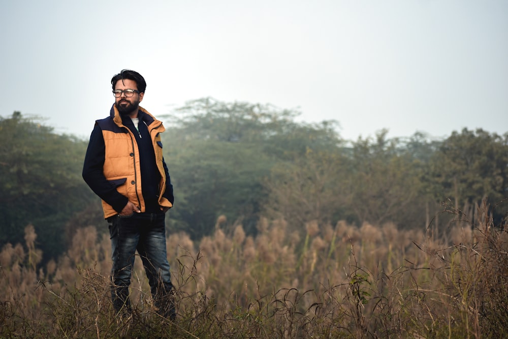 a man standing in a field with trees in the background