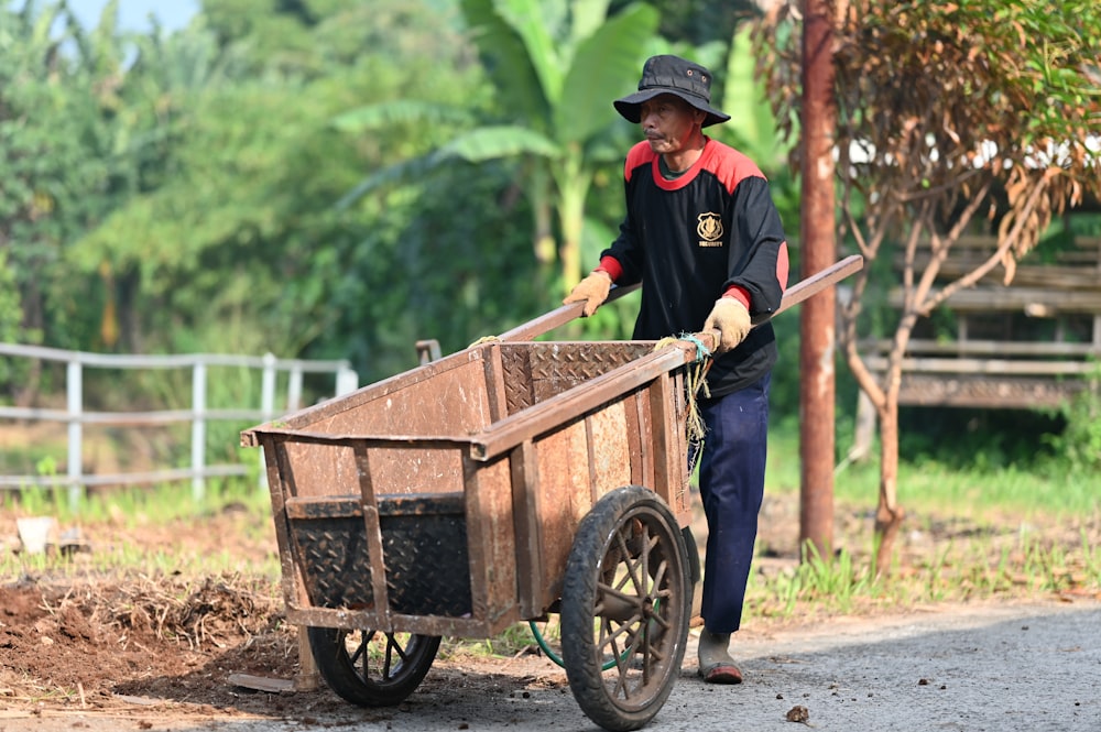 a man pushing a wheelbarrow down a road