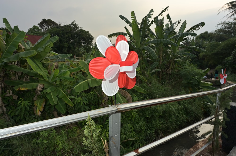 a red and white pinwheel sitting on top of a metal rail