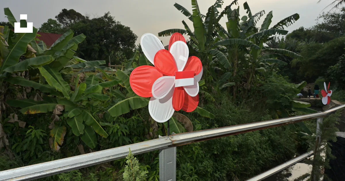 A red and white pinwheel sitting on top of a metal rail photo – Free ...