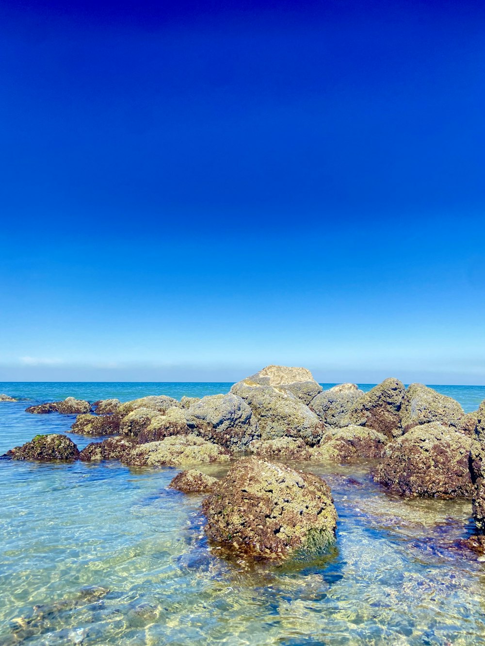 a rocky beach with clear blue water under a blue sky