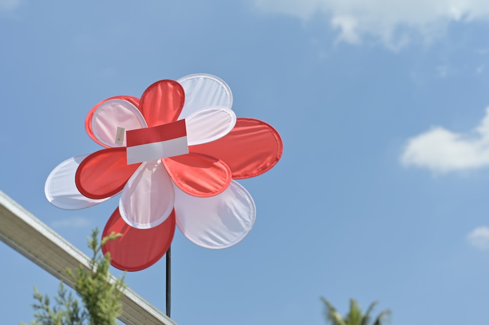 a red and white flower shaped kite flying in the sky