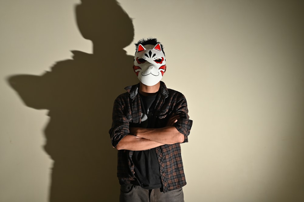 a man wearing a mask standing in front of a wall