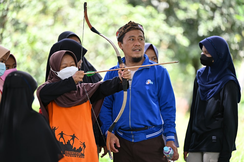 a man holding a bow and arrow in front of a group of people