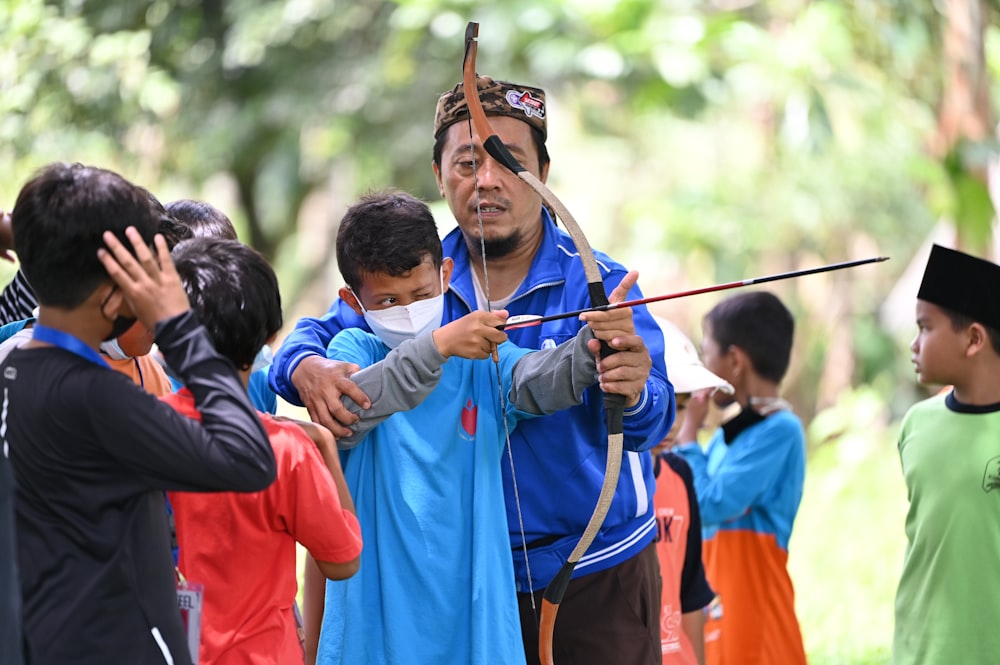 a man holding a bow and arrow in front of a group of people