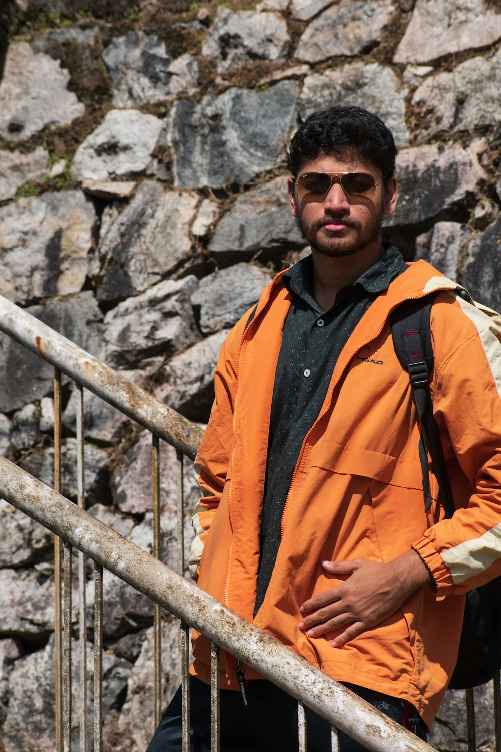 a man in an orange jacket is standing on a set of stairs