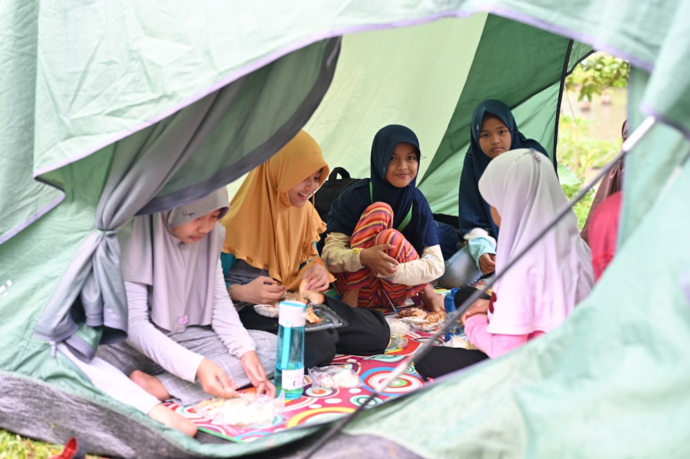 a group of women sitting around a tent