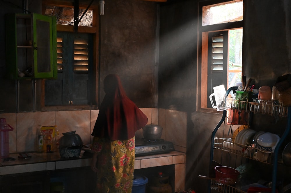 a woman standing in a kitchen next to a window