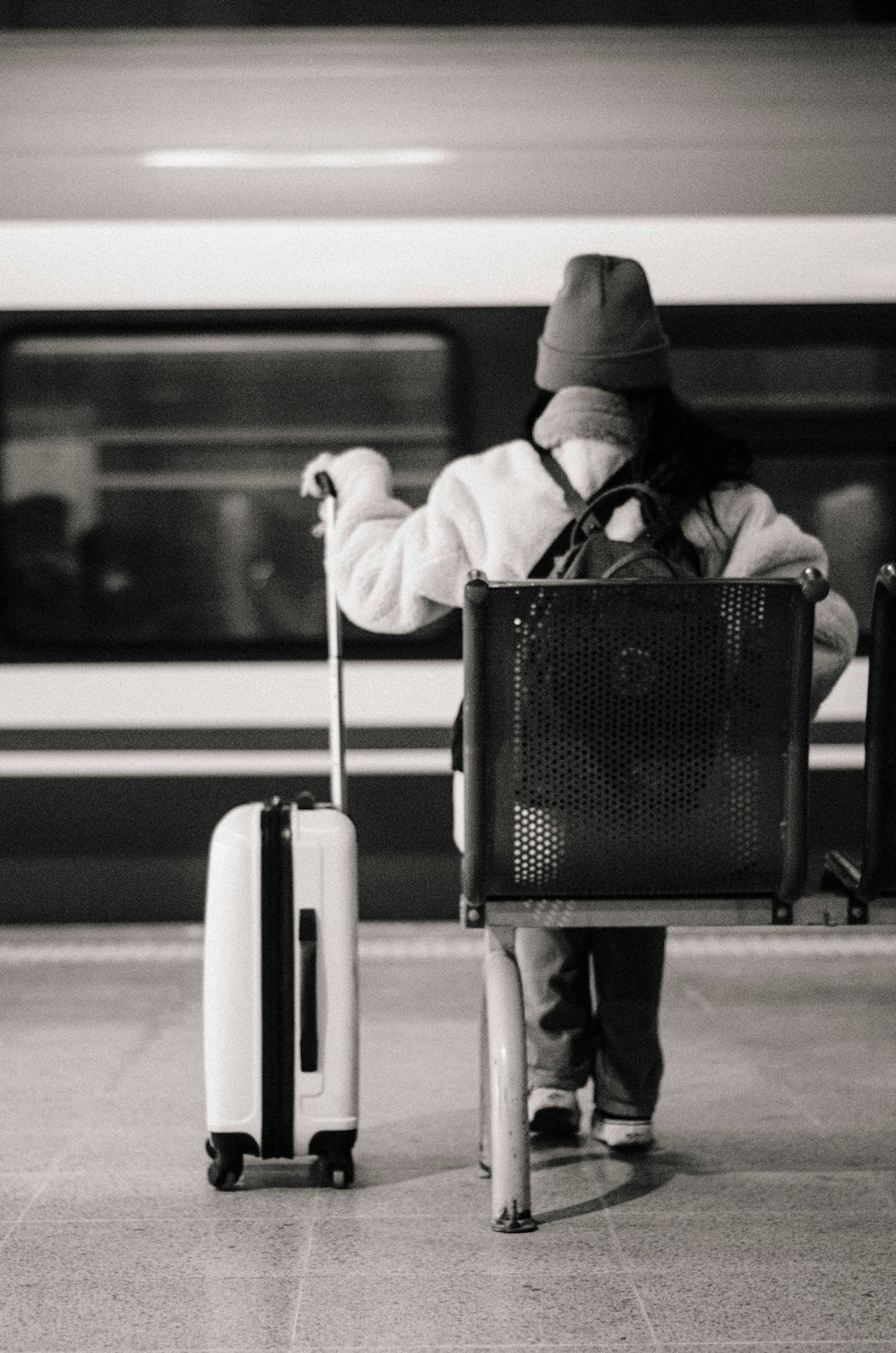 a person with a suitcase and a bag waiting for a train