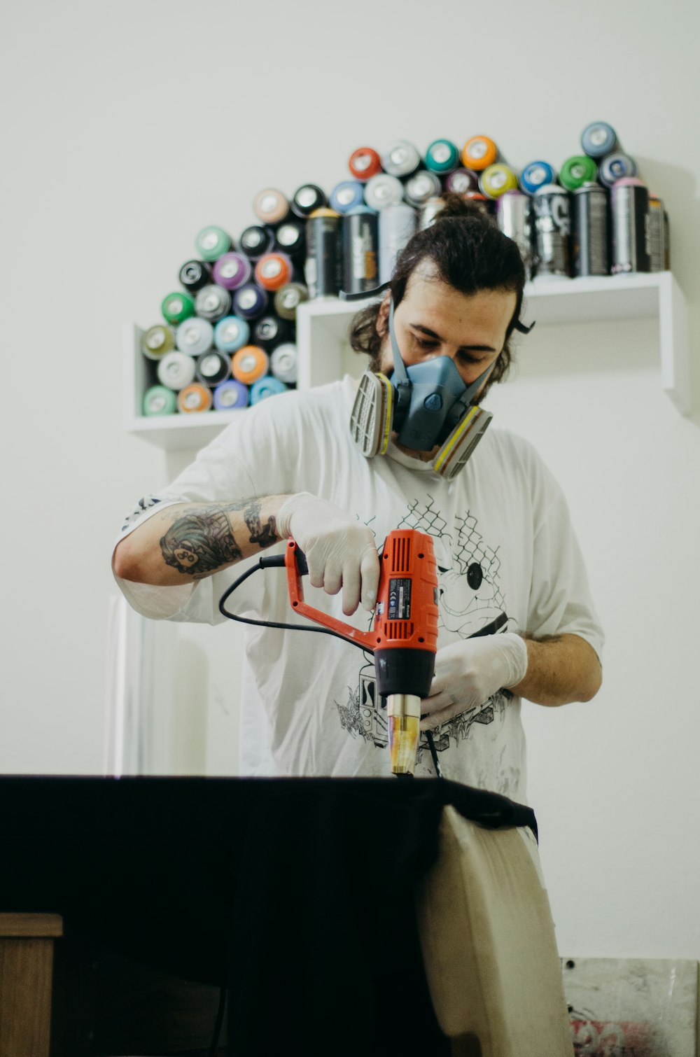 a man with a mask and gloves on working on a piece of furniture