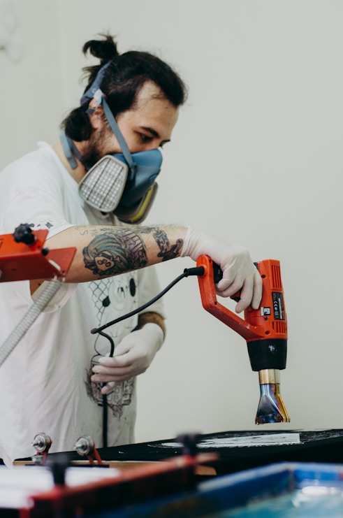 a man with a mask and gloves on working on a piece of art