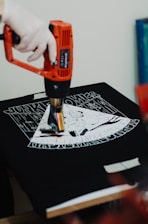 a person using a drill gun on a t - shirt