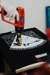 a person using a drill gun on a t - shirt