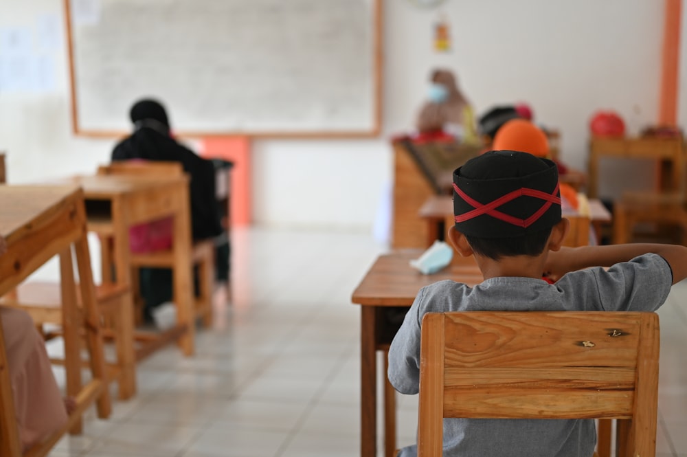 a young boy sitting at a desk in a classroom