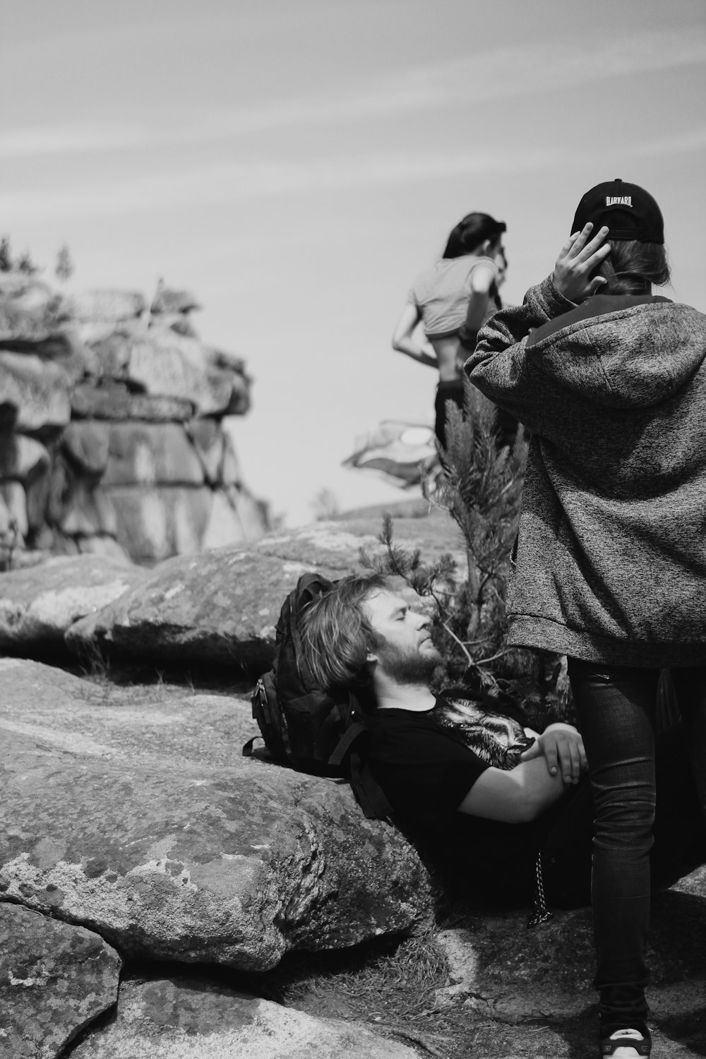 a woman sitting on top of a rock next to a man