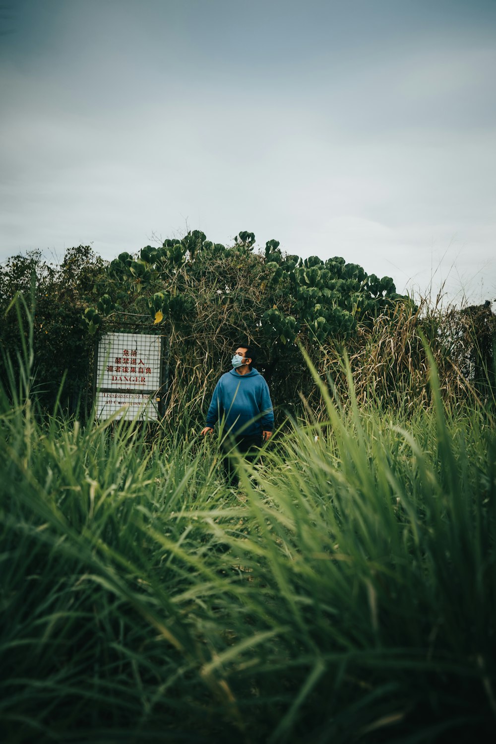 a man standing in tall grass next to a sign