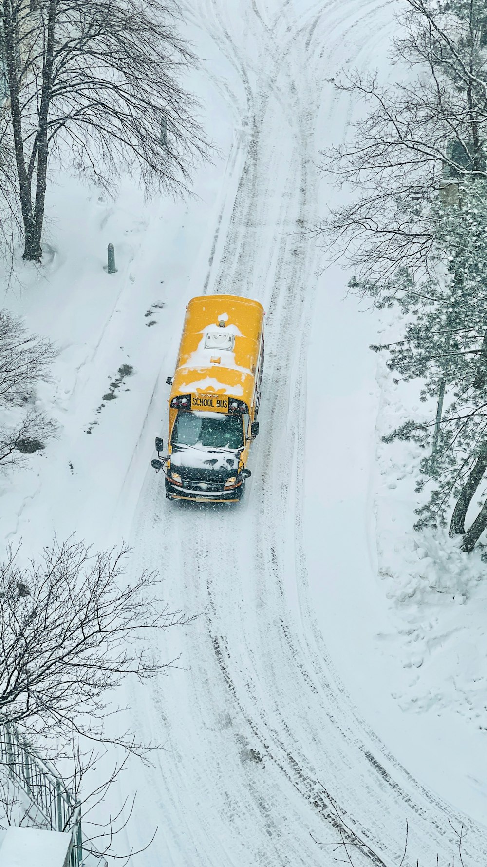 a yellow school bus driving down a snow covered road