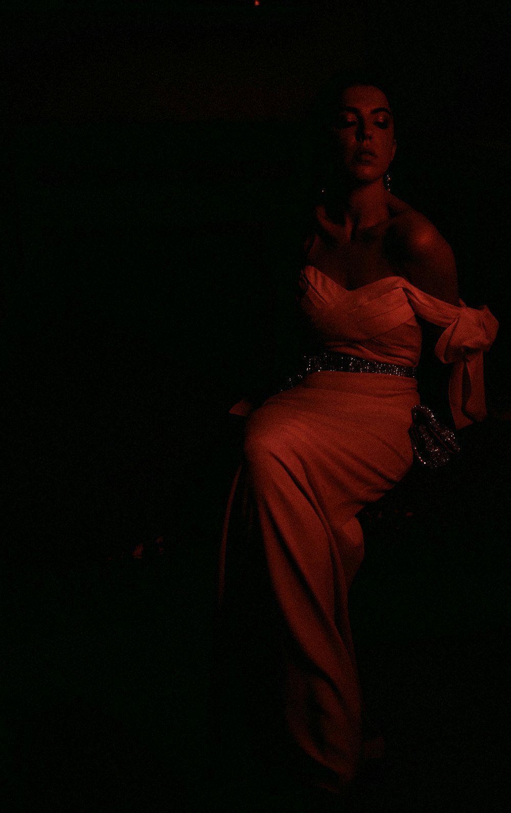 a woman in a red dress sitting in the dark